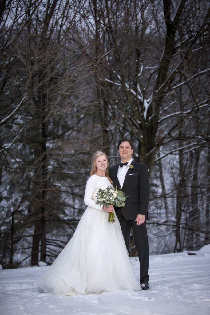 Couple pose together amongst the snowy trees for Holland, MI AirBNB wedding