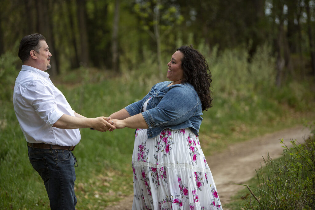 Couple holding hands and spinning Kensington Metropark engagement photos