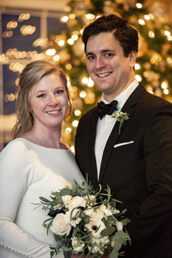 AirBNB wedding couple in front of Christmas tree lit with white lights