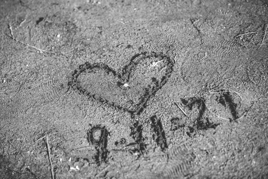 Black and white version of heart and wedding date drawn in the sand during Kensington Metropark engagement session