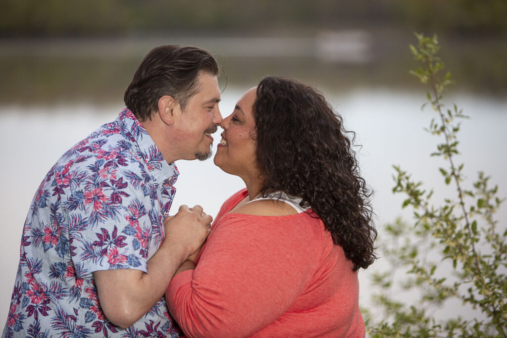 Couple kissing on the bank of Kent Lake during their Kensington Metropark engagement photos