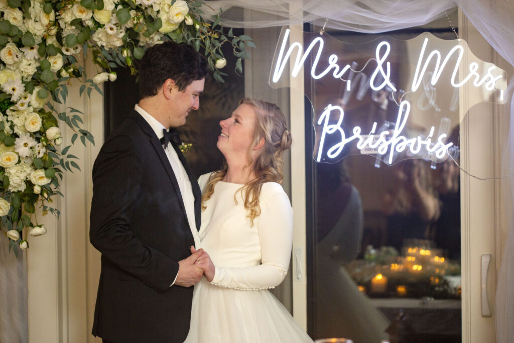 Michigan AirBNB wedding couple looking at each other in front of custom neon wedding sign