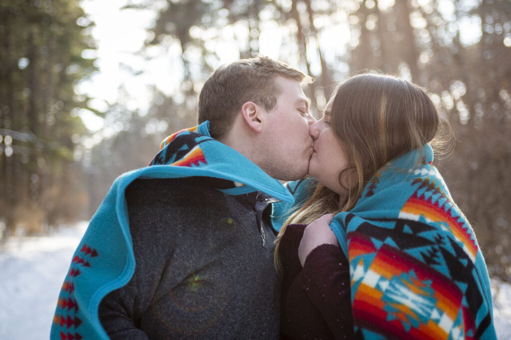 Couple kisses in blanket during their winter couple's photos