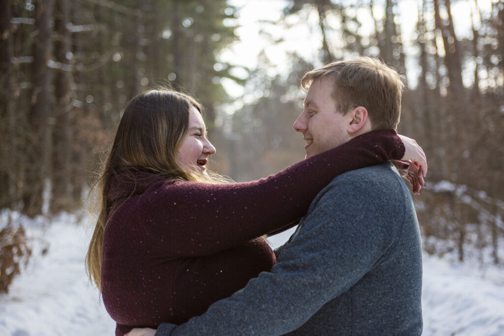 Husband and wife embrace in Dexter woods during their winter couple's photos