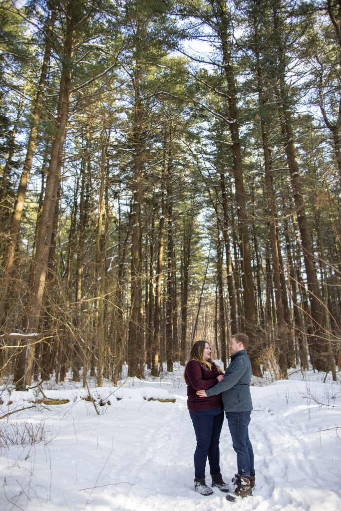 Dexter Michigan woods couple stands amongst tall pines during winter couple's photos