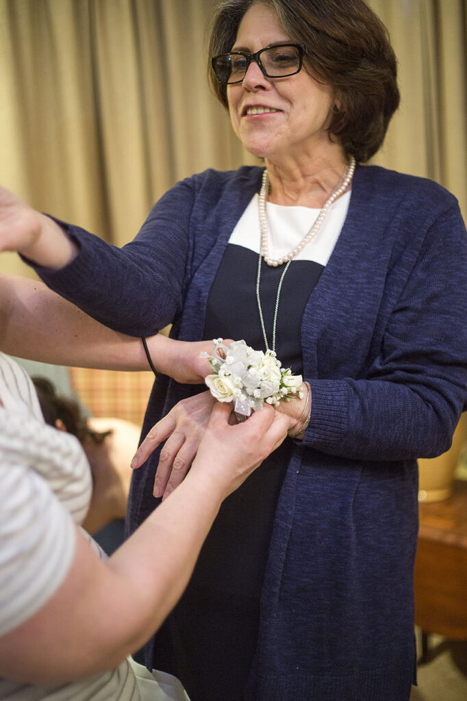 Mother of the bride getting her corsage put on her wrist at the Plymouth wedding