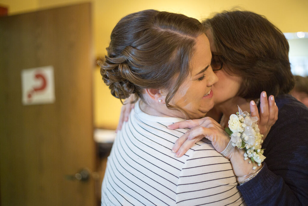 Bride making funny face when her mom kisses her cheek before her Plymouth wedding