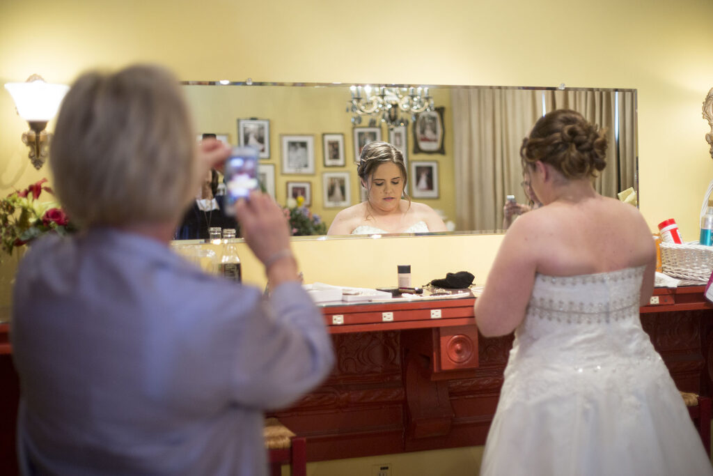 Mother taking photo of bride getting ready at their Plymouth wedding