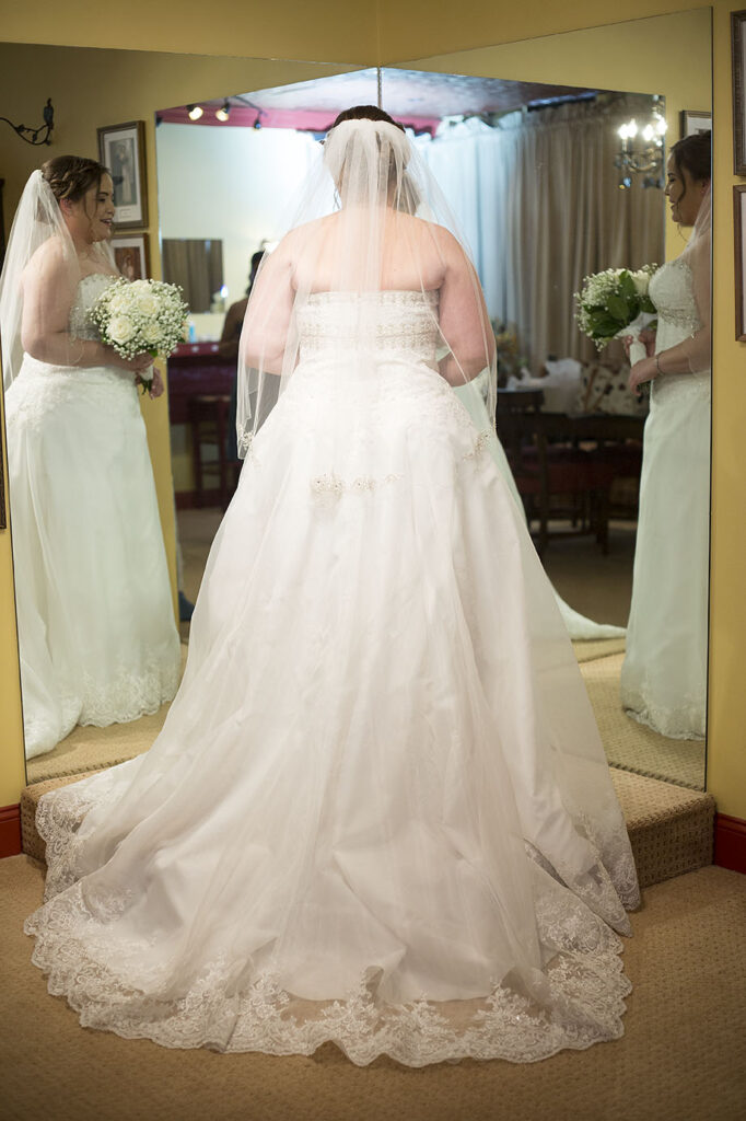 Bride standing in front of mirror before her Plymouth wedding