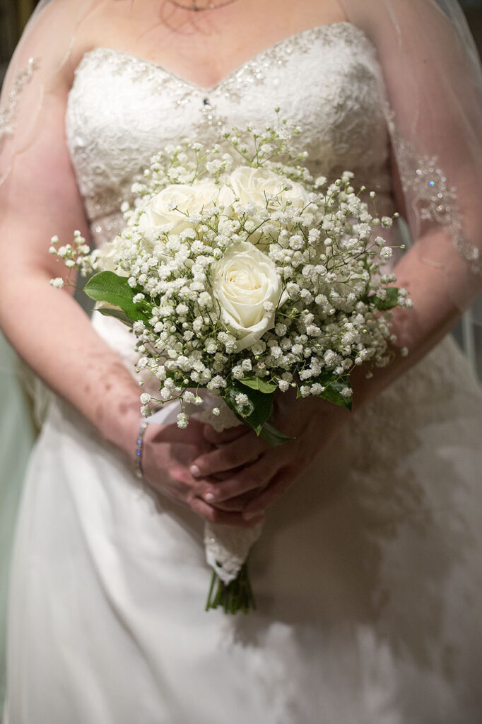 Bride holding her bouquet of white roses and babies breath at Plymouth wedding