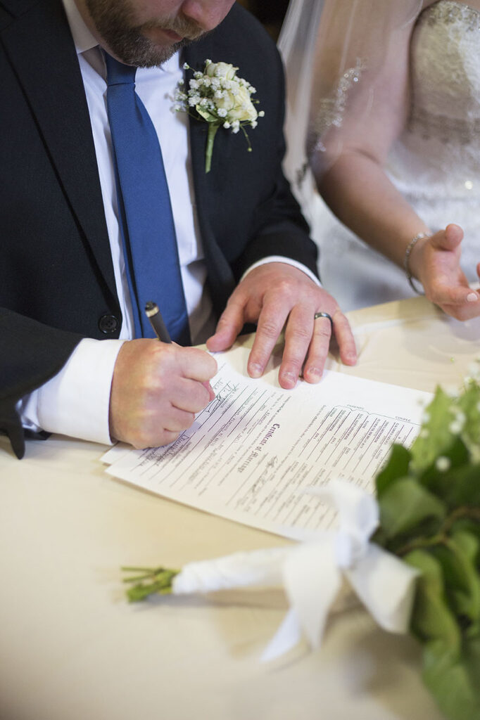 Groom signing marriage certificate at Plymouth wedding