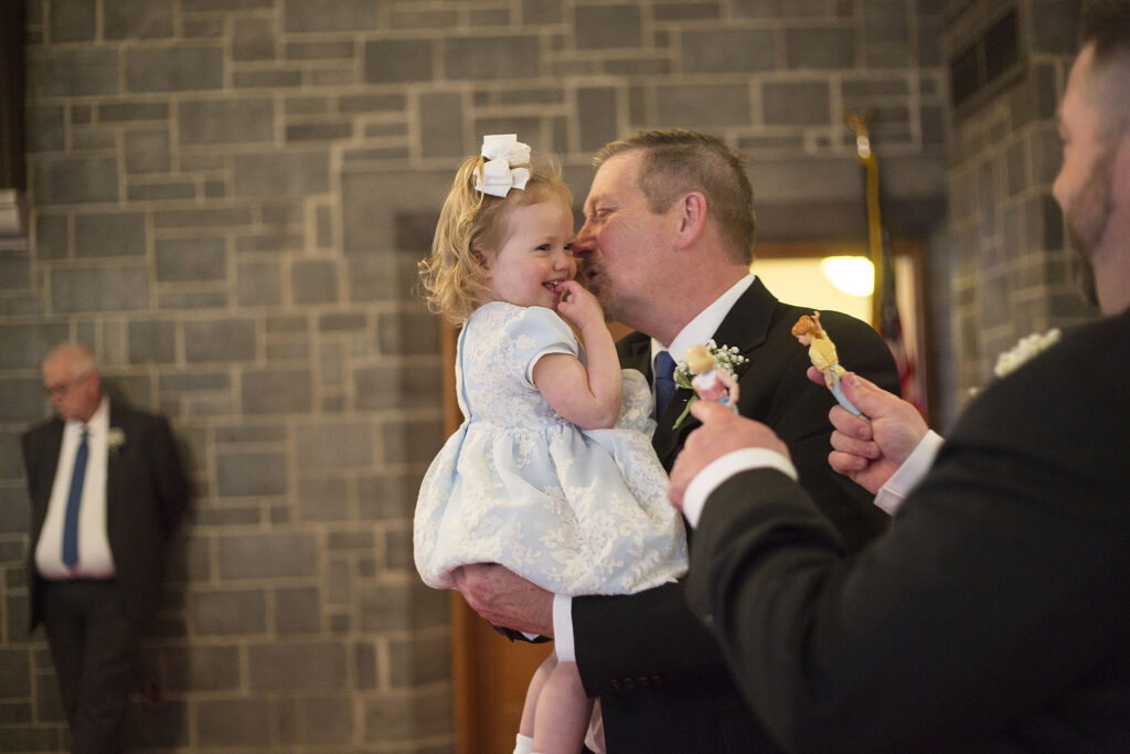 Grandfather kissing granddaughter's cheeks at Plymouth wedding