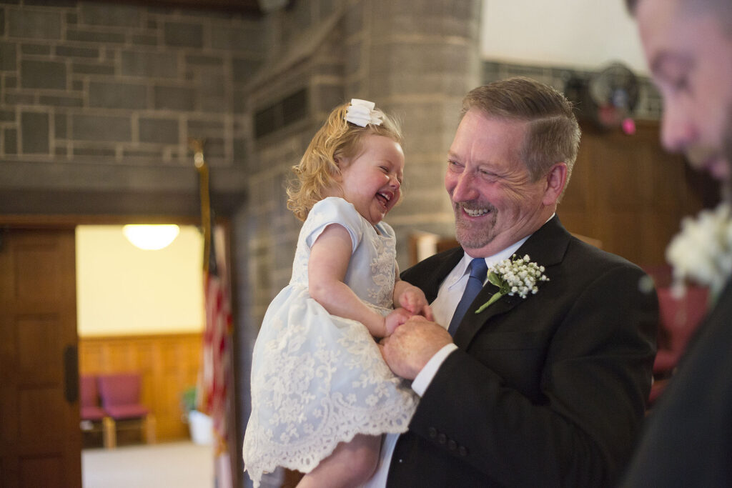 Granddaughter and grandfather laughing together at Plymouth wedding