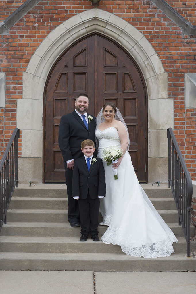 Plymouth wedding couple stands with son in front of church