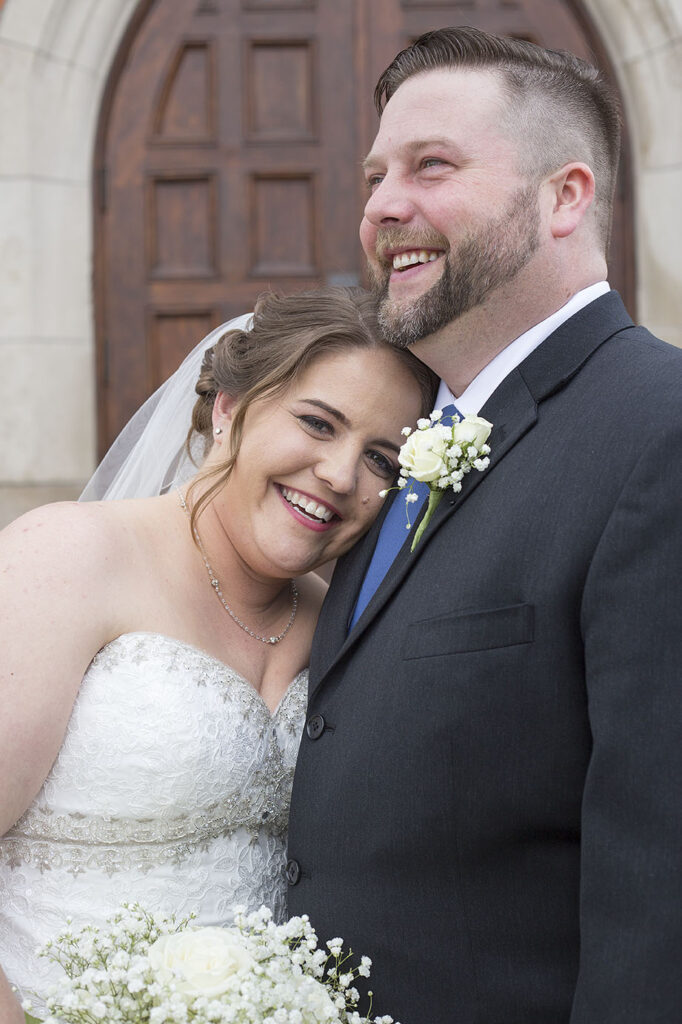 Plymouth wedding couple cuddling in front of church doors