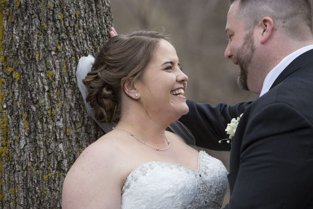 Plymouth wedding couple leans up against tree and smiles at each other