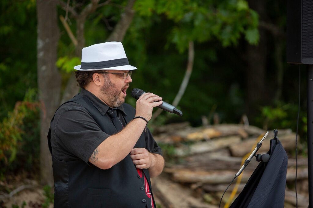 Officiant at an Elk Rapids wedding sings "I'll Cover You" from Rent as the couple walks down the aisle.