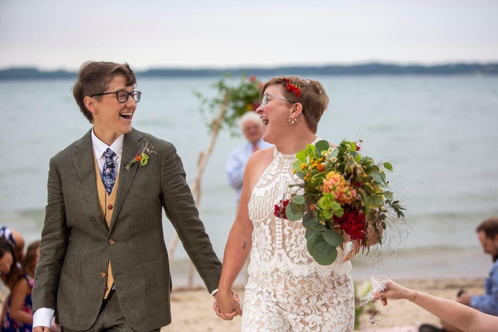 Elk Rapids LGBTQ wedding couple laughing together as they just announced them as officially married.