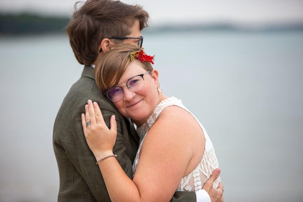 Bride cuddles on her wife's shoulder during their Elk Rapids wedding.