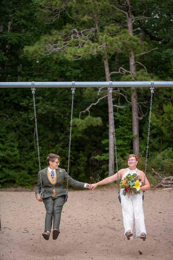 Michigan same sex wedding couple swings on park swings.