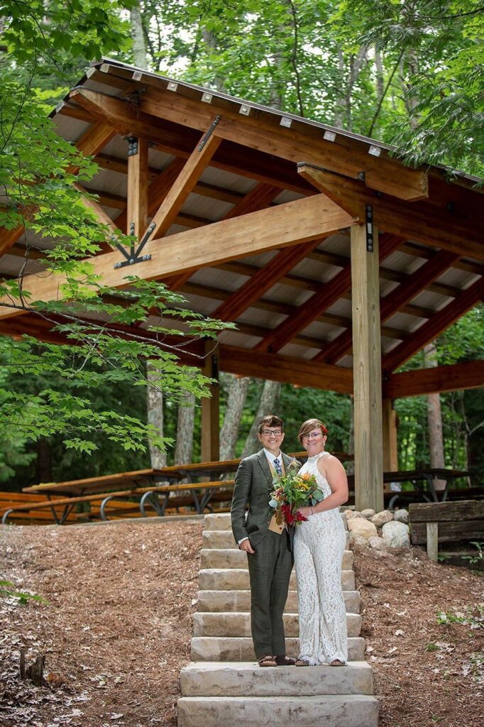 Elk Rapids wedding couple poses on steps in front of Elk Rapids Day Park pavillion.