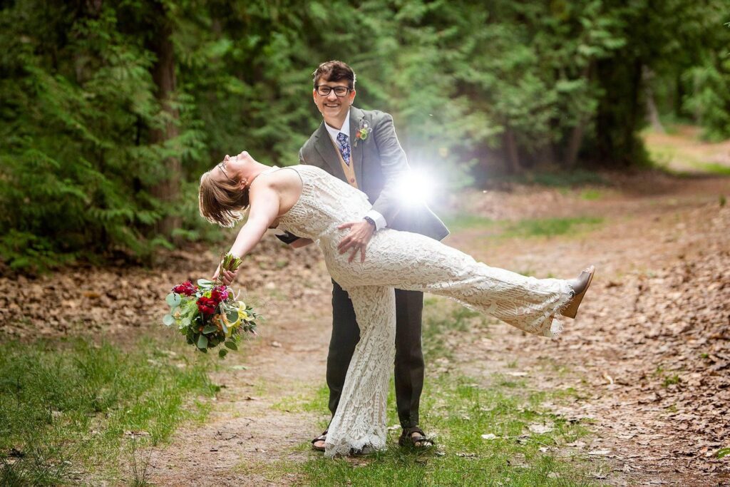 Michigan LGBTQ wedding photographer has woman hold her wife as she prepares to dip and kiss her.