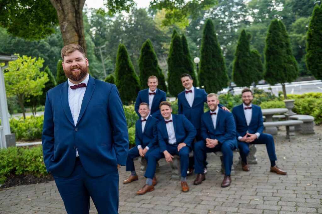 Groom stands in front of groomsmen at Saline wedding.