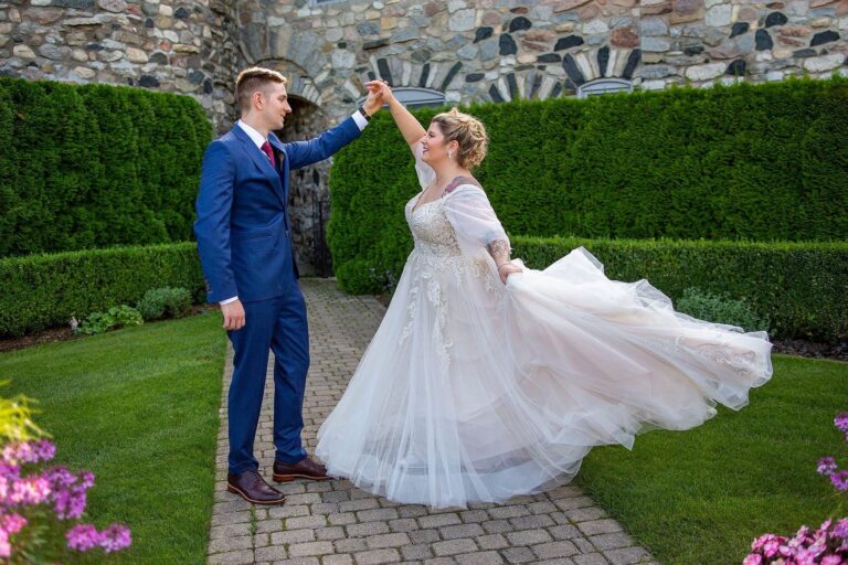 Groom twirls bride in Castle Farms courtyard.