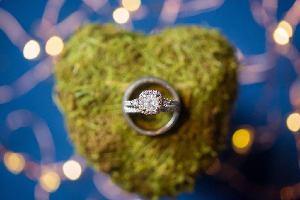 Wedding rings on moss covered heart.