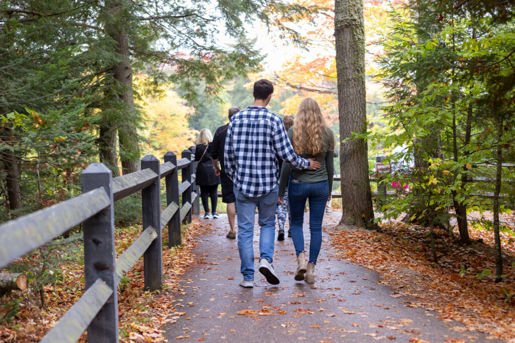 Tahquamenon Falls engagement couple walks on a path at the upper falls.