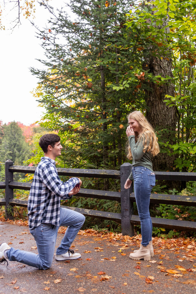 Lucas down on one knee proposing to Kassidy at Tahquamenon Falls photographer