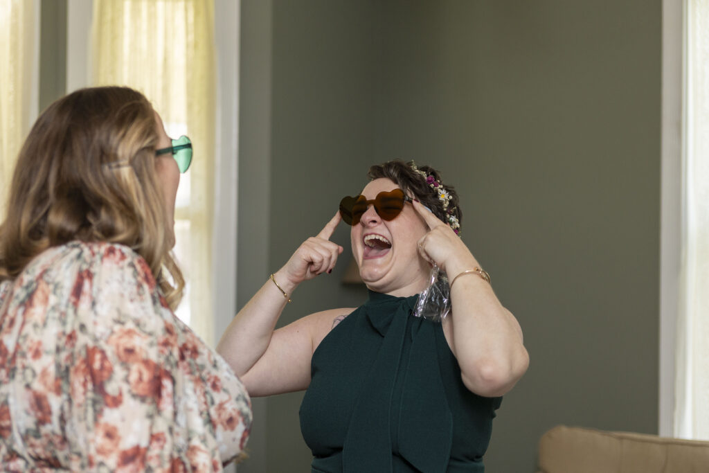 Jillian tries on heart shaped sunglasses after their Ishpeming AirBNB wedding.