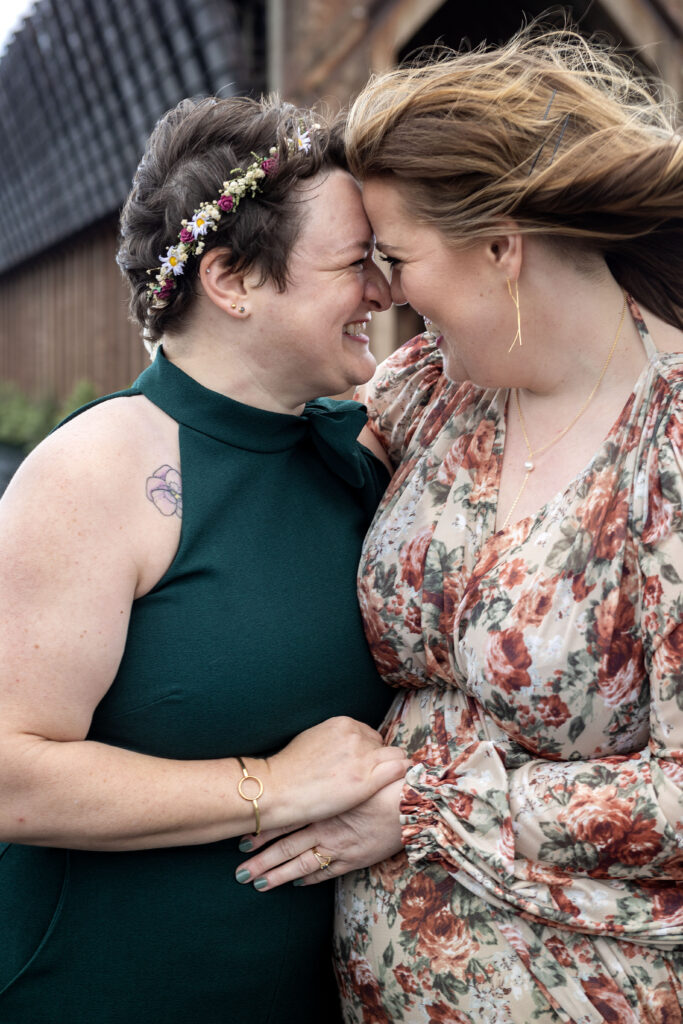 Lesbian couple cuddles up on Lake Superior's shoreline for their Marquette wedding photographer.