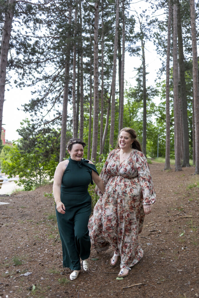 Marquette wedding couple runs through the tall pine trees along Lake Superior's shoreline.