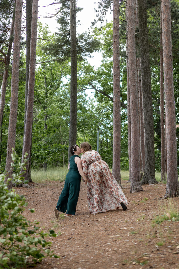 Michigan LBGT wedding photographer captures couple kissing amongst the tall pine trees in Marquette.