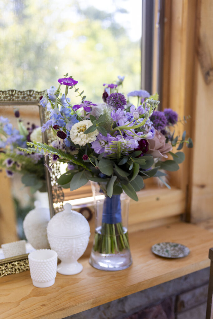 Purple floral arrangement on cabin windowsill