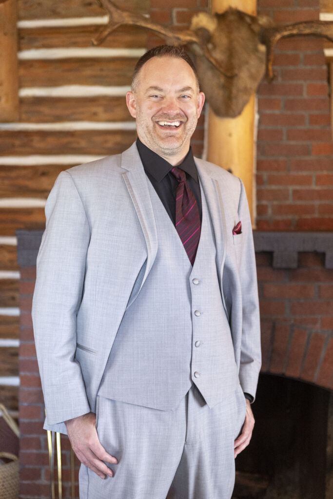 Groom smiling inside one of the historic cabins in Republic Michigan