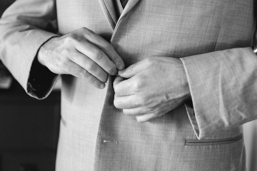 Groom buttoning his suit jacket before walking down the aisle