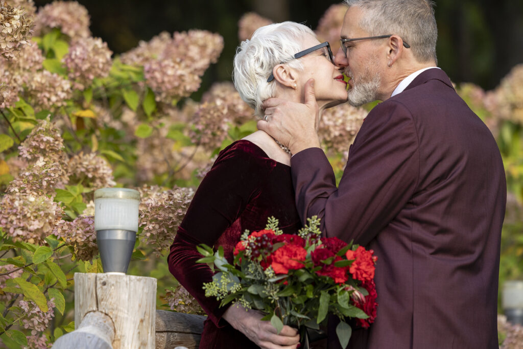 Couple kissing in front of dried hydrangeas during their Dexter Michigan wedding.