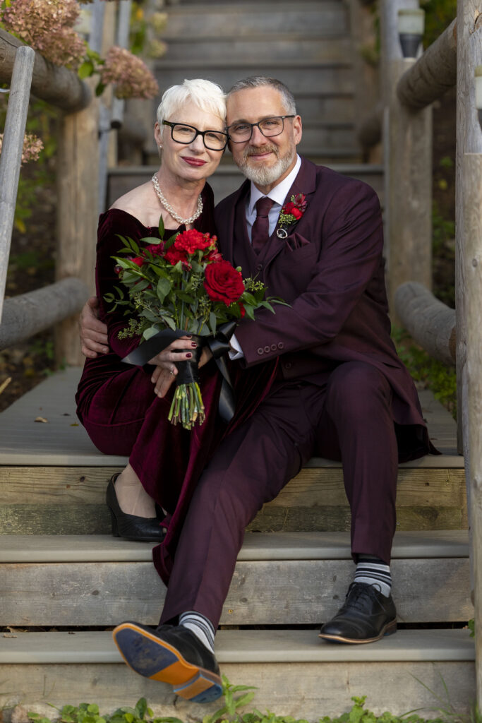 Camp Woodbury wedding couple cuddles in together on the stairs by the lake.