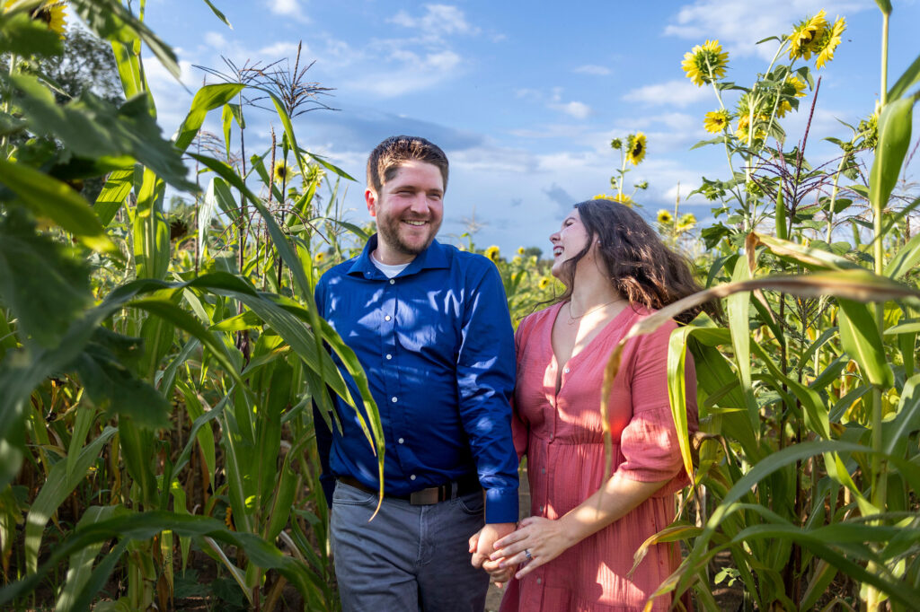 Brighton engagement photographer takes photos of couple running through sunflower field.