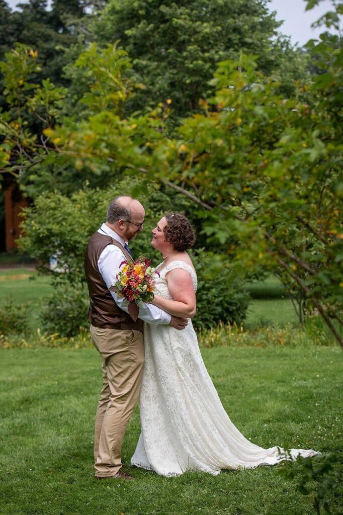 Bride and groom look at each other amongst the trees.