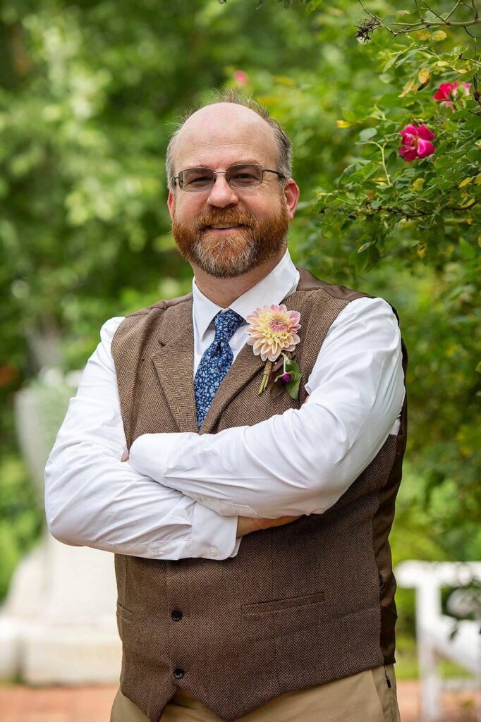 Groom stands among the roses