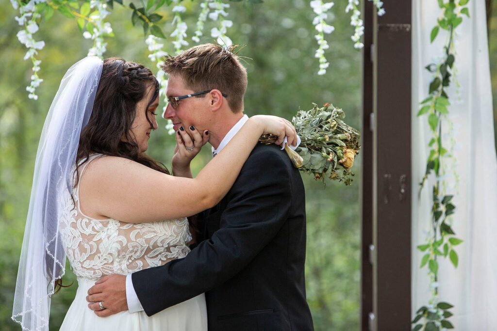 Bride pulls groom in for a kiss at Irish Hills Barn and Convention Center