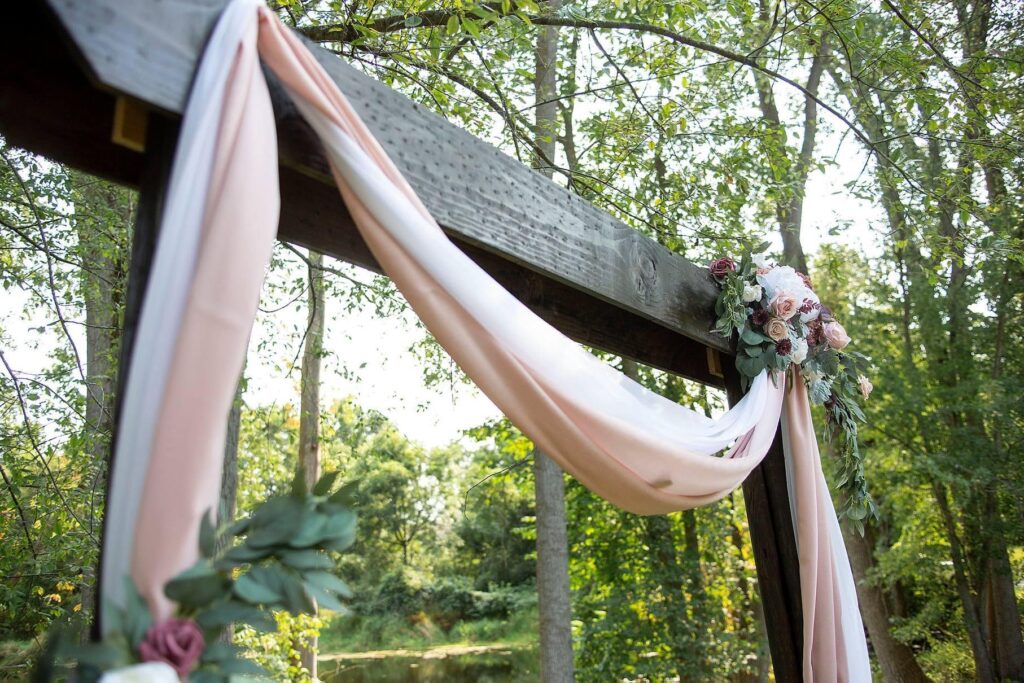 Beautiful wedding arch decorated with pale pink fabric and florals