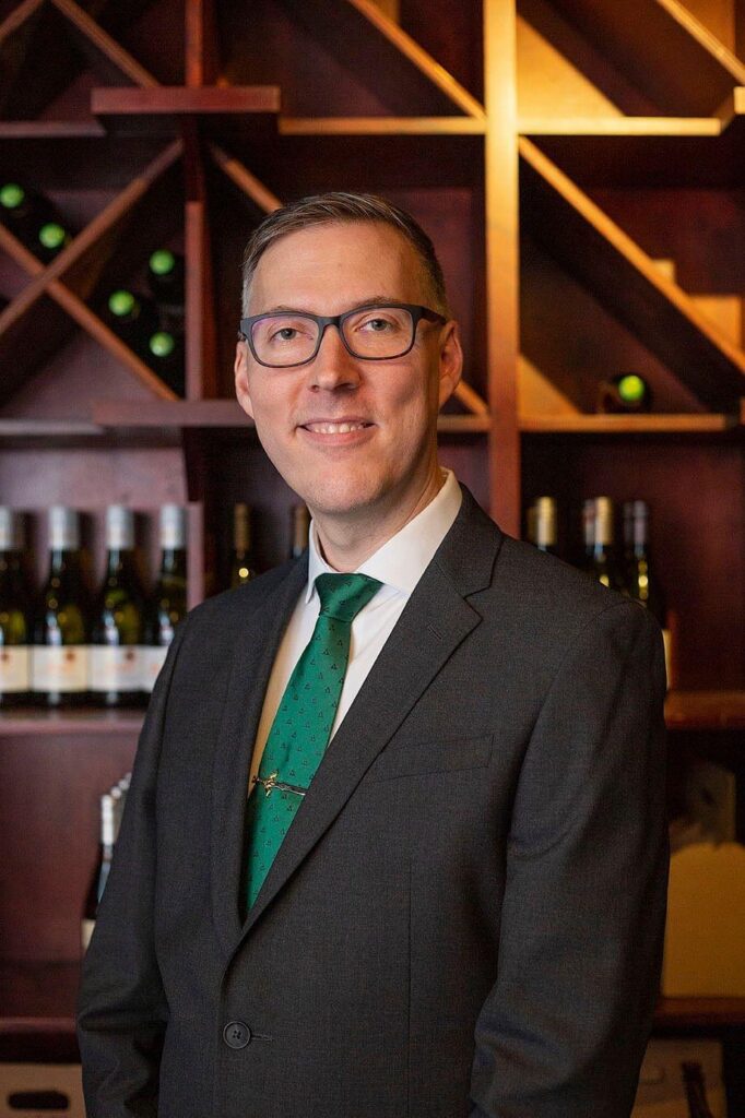 Groom stands in the wine cellar at Vinology wedding.