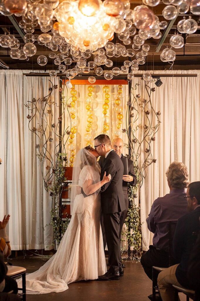 Couple kissing in their Bubble Room wedding at Vinology