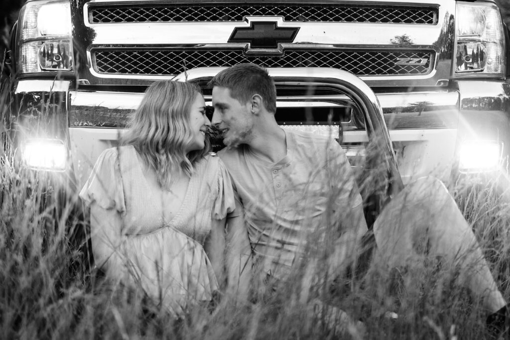 Talia leaning into Dakota as they sit in front of the truck, their foreheads touching sweetly