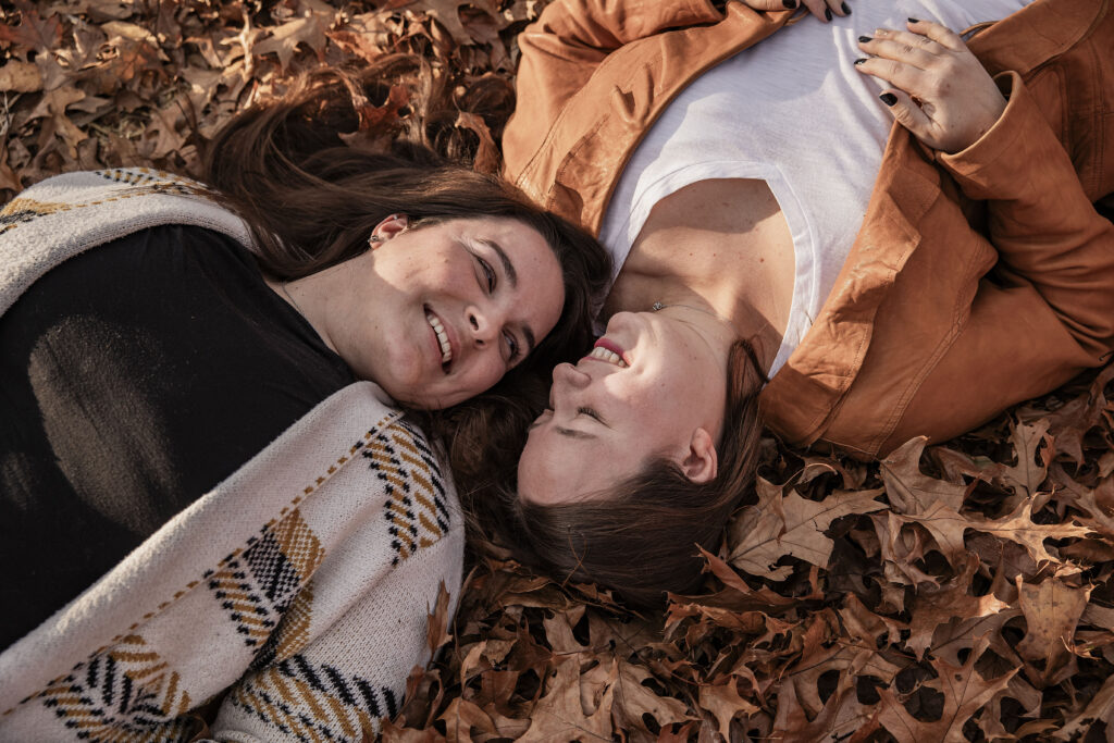 Couple laughs in the fallen leaves during autumn photos