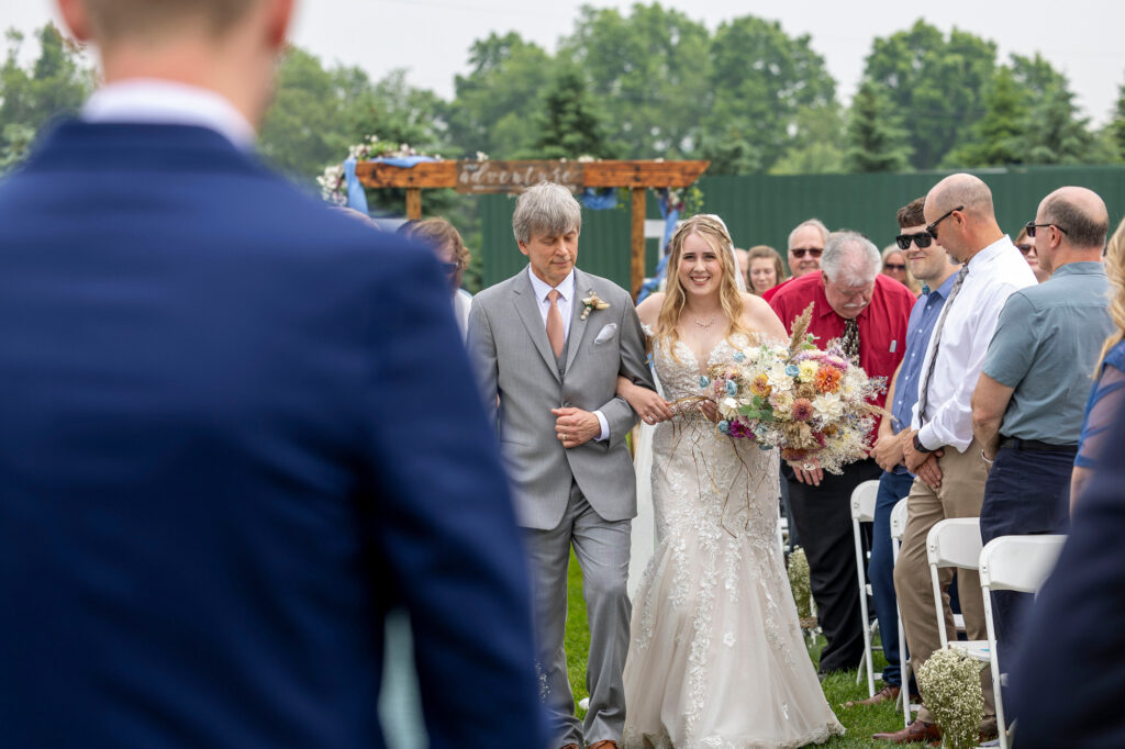 Bride walking down the aisle with her father at The Rustic Wedding Barn